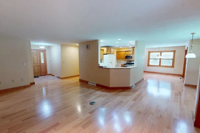 a living room with wooden floors and a kitchen