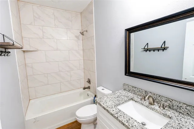 a bathroom with a granite countertop sink a toilet and shower