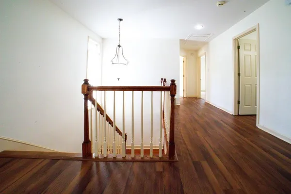 a view of a hallway with wooden floor and staircase