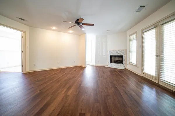 a view of empty room with wooden floor fireplace and a window