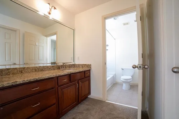 a bathroom with a granite countertop sink mirror and toilet