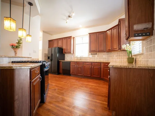 a kitchen with stainless steel appliances granite countertop a stove a sink dishwasher a refrigerator and a microwave oven with wooden floor