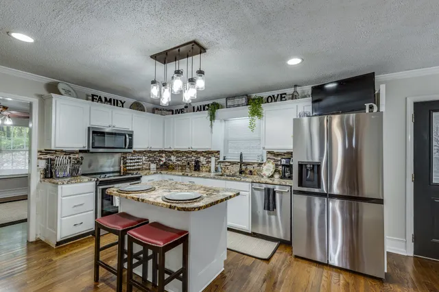 a kitchen with stainless steel appliances granite countertop a sink stove and refrigerator