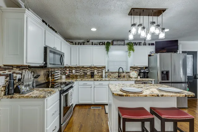a view of a dining room and livingroom with furniture wooden floor a chandelier