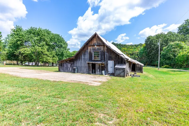 a view of a house with a big yard and large trees