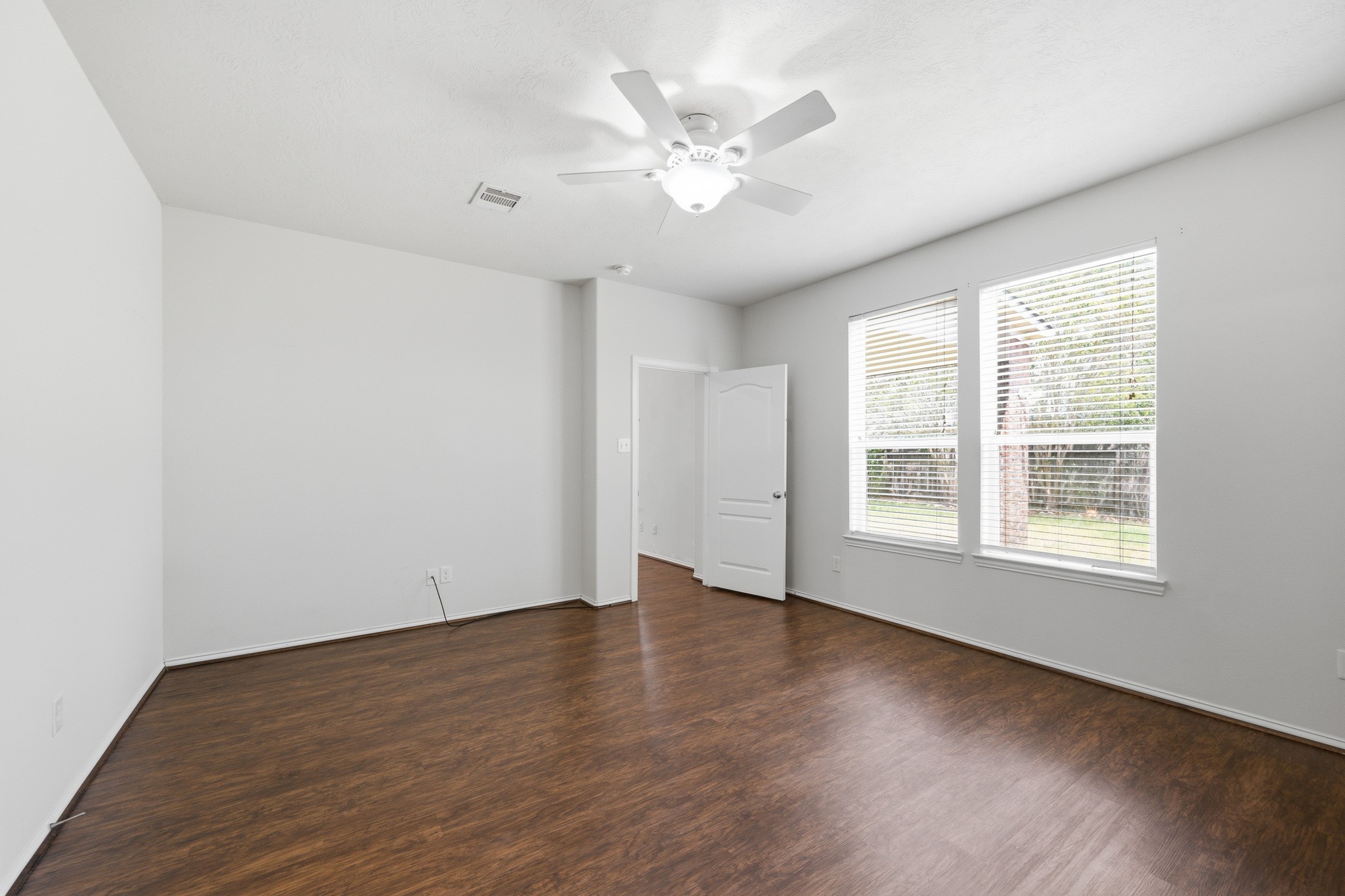 2117 Rushing Spring Drive Pearland, TX 77584 - Photo 22 of 42 Experience serene comfort in this spacious primary bedroom, featuring elegant hardwood floors, abundant natural light, and a modern ceiling fan for ultimate relaxation.