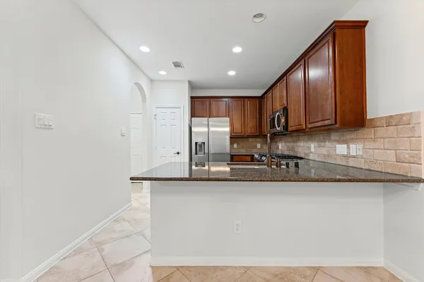 a kitchen with stainless steel appliances granite countertop a sink a stove and a refrigerator