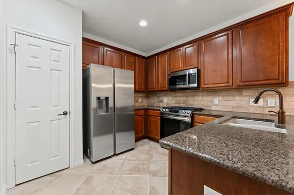 a kitchen with stainless steel appliances granite countertop a refrigerator stove and sink