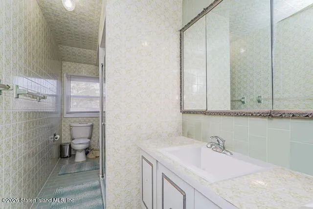 a bathroom with a granite countertop sink a toilet and a shower