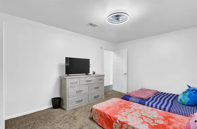 an empty room with ceiling fan and window