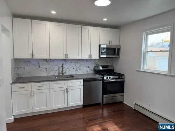 a kitchen with granite countertop white cabinets and black appliances