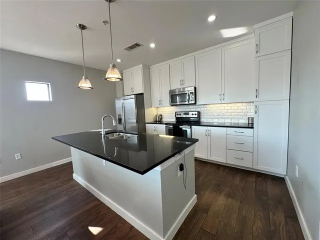 a kitchen with kitchen island granite countertop a sink a counter space appliances and cabinets