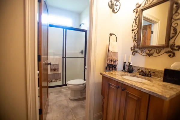 a bathroom with a sink vanity granite toilet and a mirror