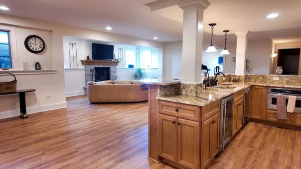 a kitchen with a stove top oven a sink dishwasher a dining table and chairs with wooden floor