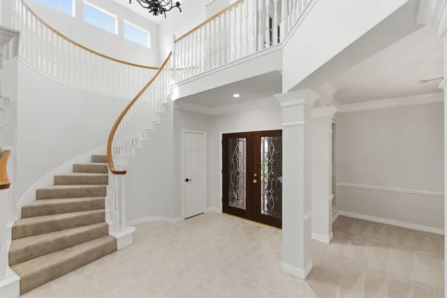 an empty room with chandelier fan and windows