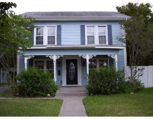 a view of a brick house with a yard potted plants and a table