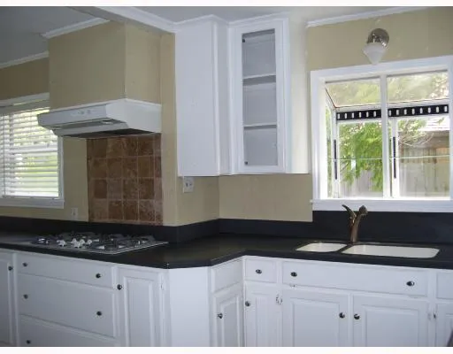 a kitchen with granite countertop a sink a stove and cabinets