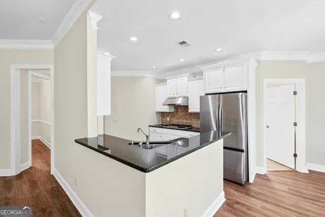 a kitchen with kitchen island a refrigerator stove and wooden floor