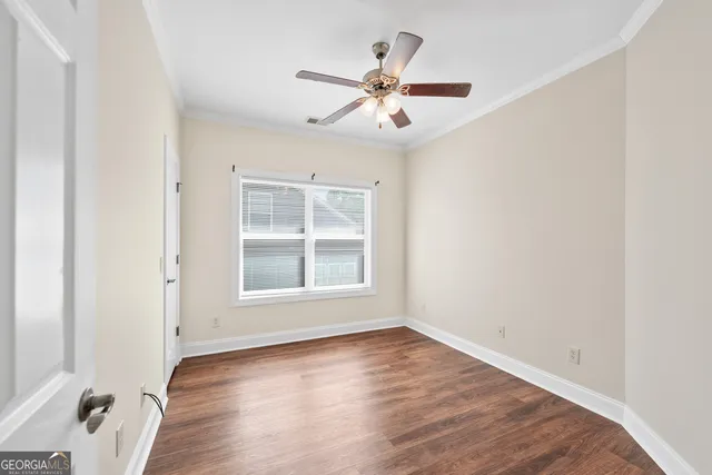 an empty room with wooden floor closet and windows