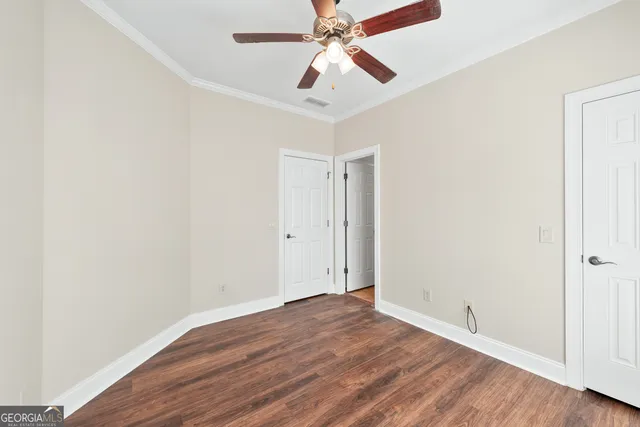 an empty room with wooden floor ceiling fan and windows