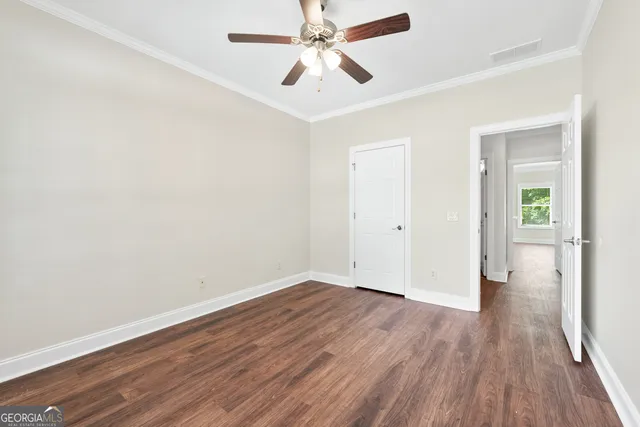 an empty room with wooden floor ceiling fan and windows