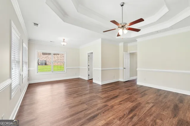 a view of an empty room with window and wooden floor