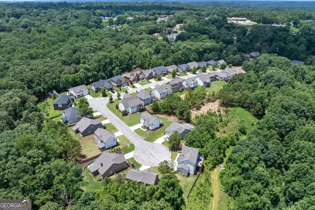 an aerial view of residential house with outdoor space and trees all around