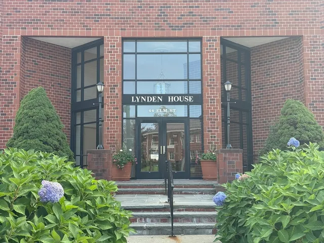 a view of a brick house with a potted plant and floor to ceiling windows