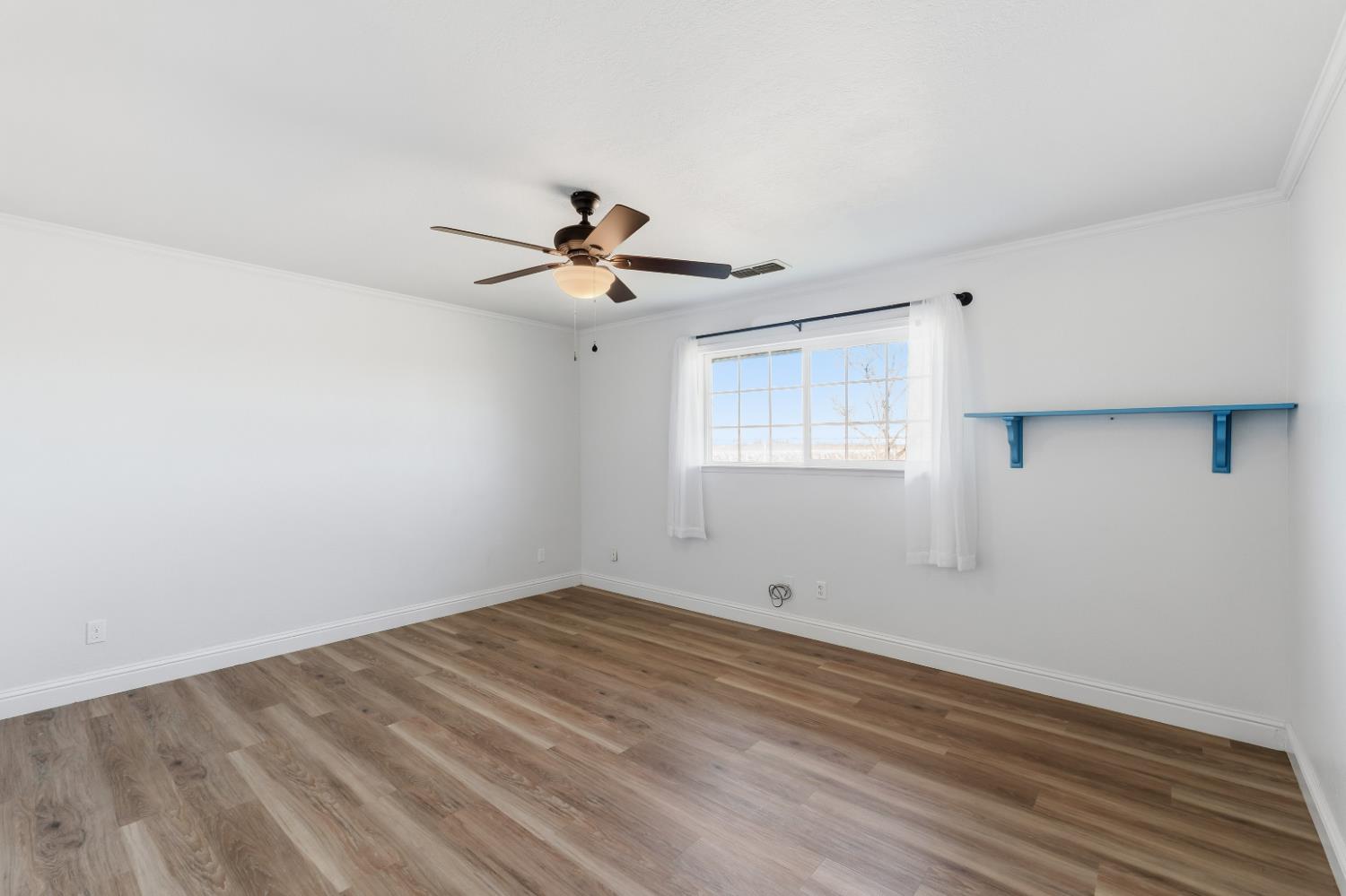 2938 North Trinity Avenue Kerman, CA 93630 - Photo 17 of 38 a view of a room with wooden floor and a ceiling fan