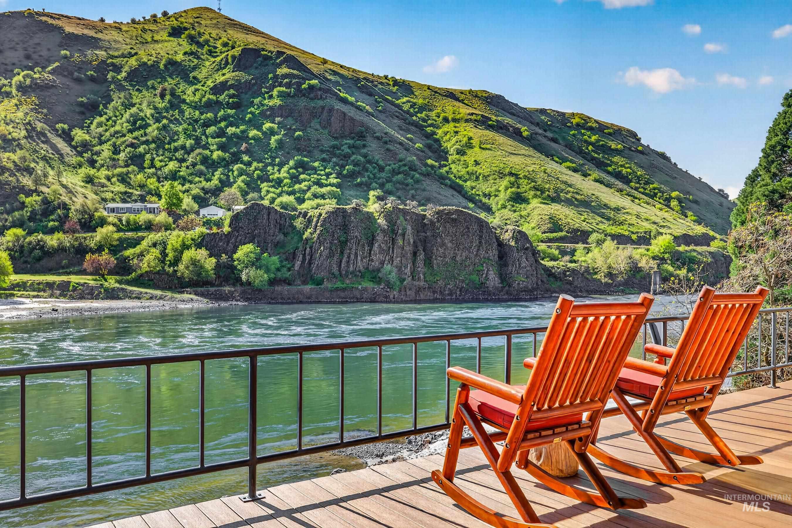 215 Doumecq Road White Bird, ID 83554 - Photo 2 of 50 Expansive outdoor deck with wood-finish flooring and black metal railing overlooking a wide river