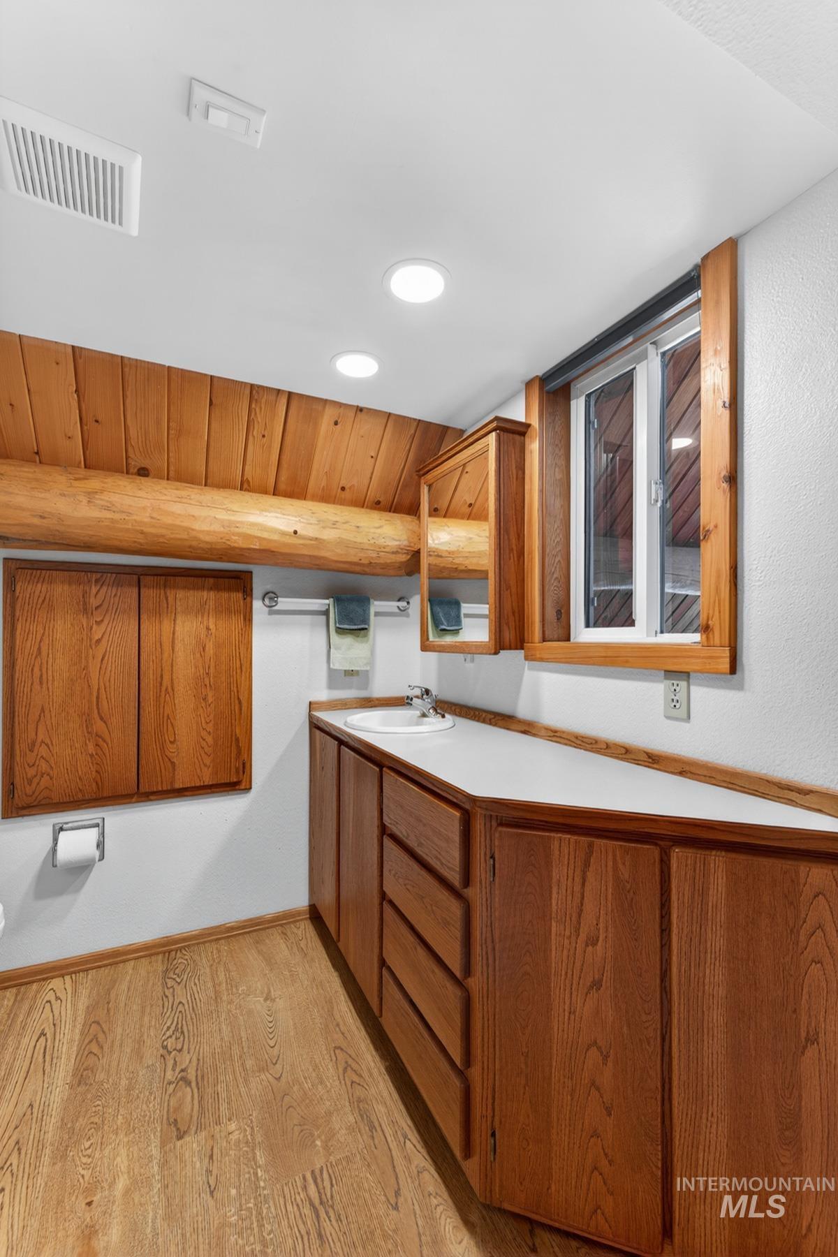 215 Doumecq Road White Bird, ID 83554 - Photo 27 of 50 Wood-finish flooring with a multi-drawer vanity featuring a white countertop and an integrated sink