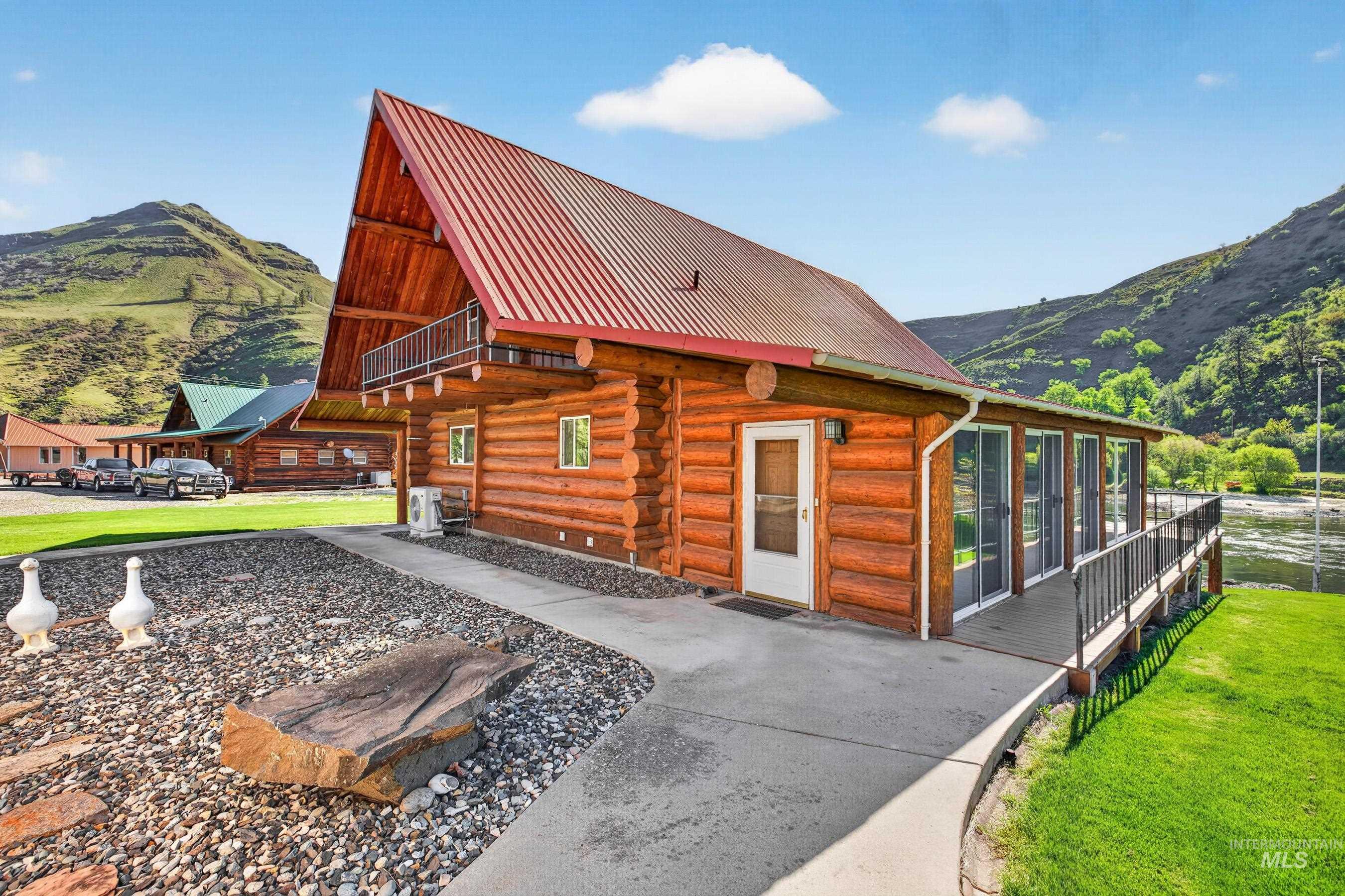 215 Doumecq Road White Bird, ID 83554 - Photo 33 of 50 Log cabin exterior featuring a red metal roof, a full-length balcony, and a covered porch with a metal railing