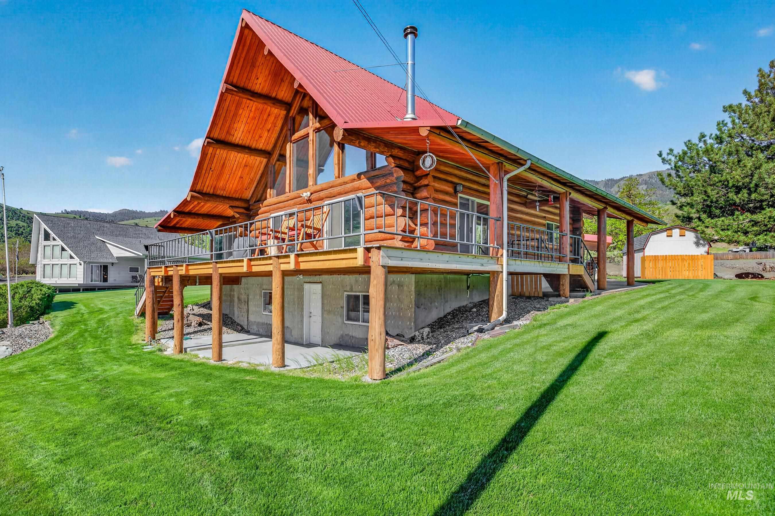 215 Doumecq Road White Bird, ID 83554 - Photo 4 of 50 Log home featuring a red metal roof, full-length deck with metal railing, and a walk-out lower level