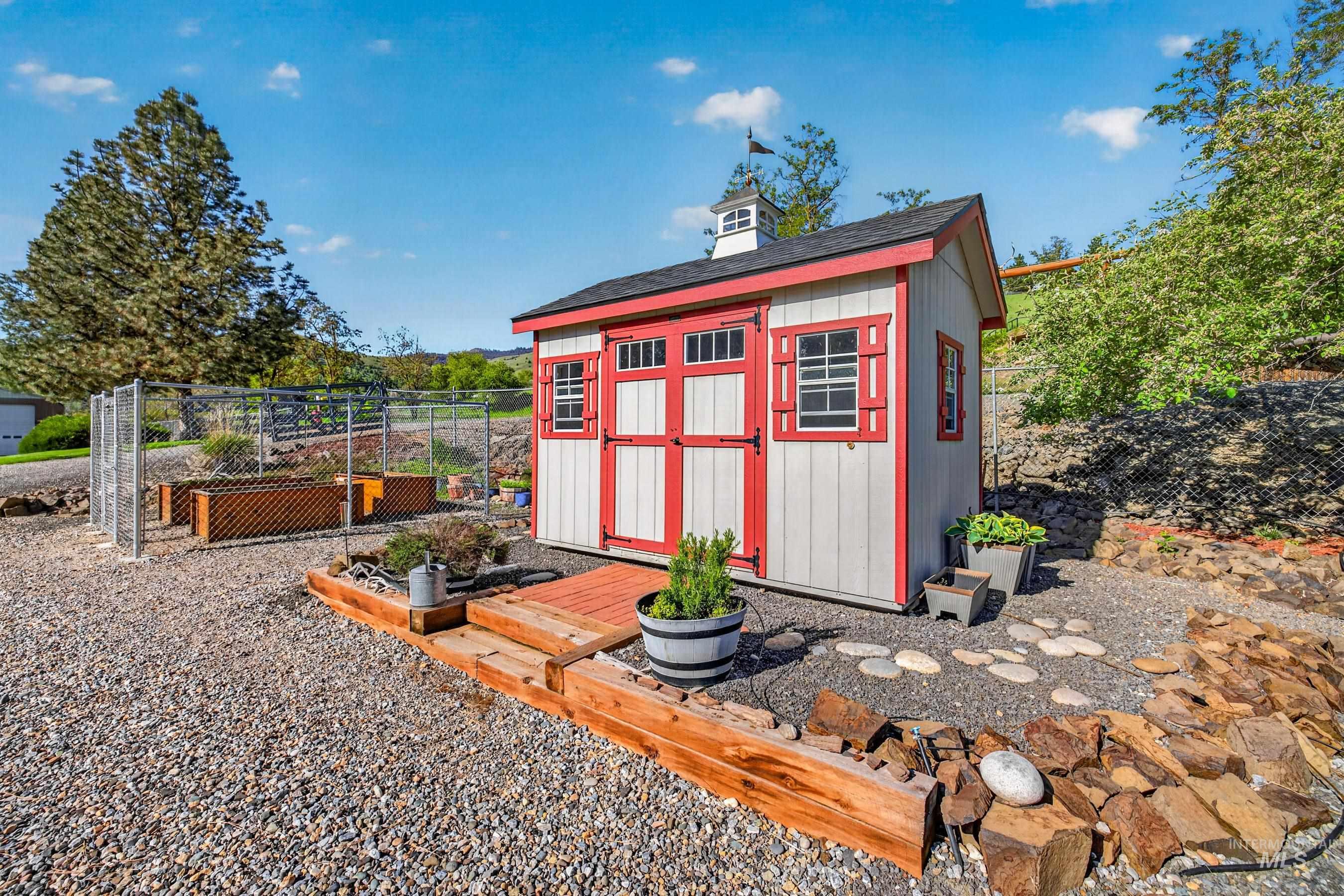 215 Doumecq Road White Bird, ID 83554 - Photo 44 of 50 Utility shed with a cupola and red trim, featuring a gravel ground cover and integrated wooden planters