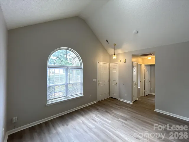 an empty room with wooden floor mirror and windows