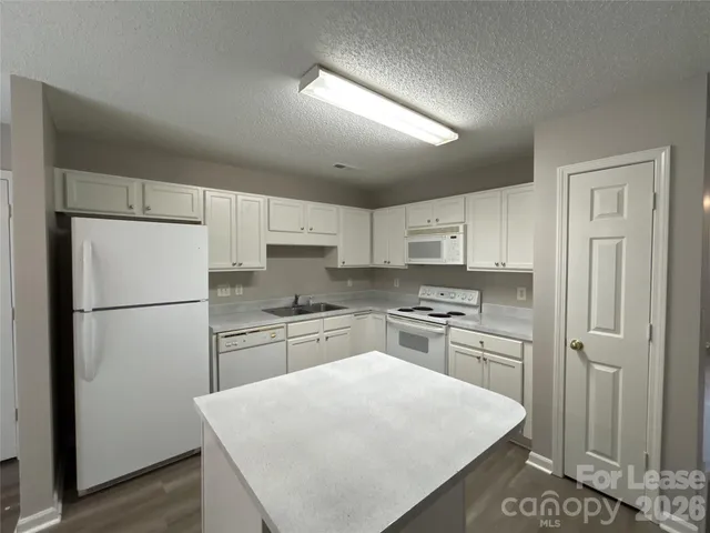a kitchen with a refrigerator a stove a sink and white cabinets