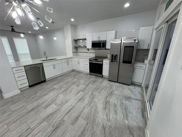 a kitchen with granite countertop a refrigerator oven a sink dishwasher and white cabinets with wooden floor