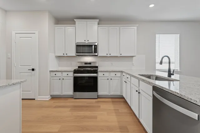 a kitchen with granite countertop white cabinets and a stove
