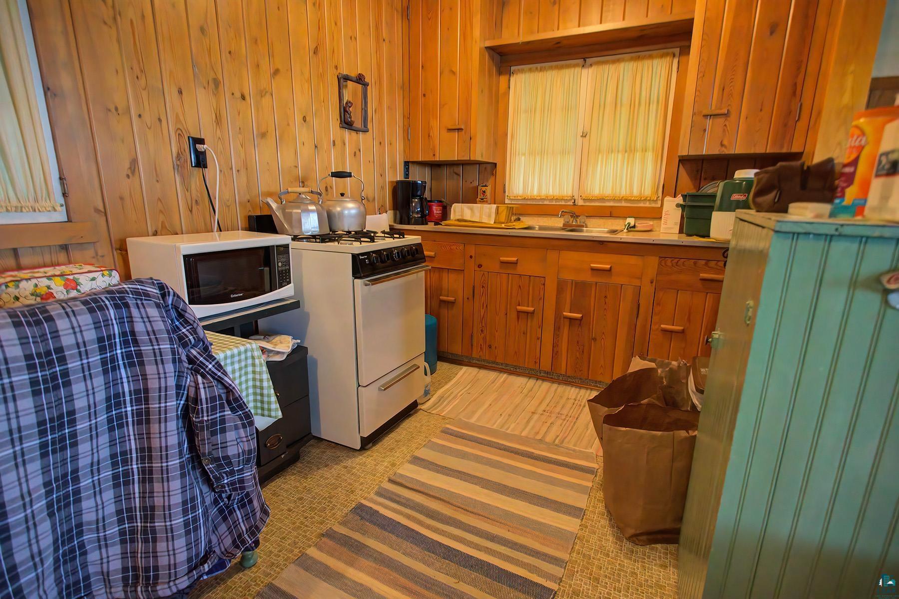 2815 Schaeffer Road Ely, MN 55731 - Photo 28 of 37 Wood-paneled walls with built-in wooden cabinetry and a window over the sink