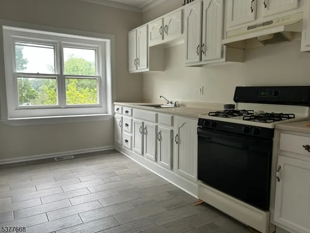 a kitchen with granite countertop a stove a sink and a microwave