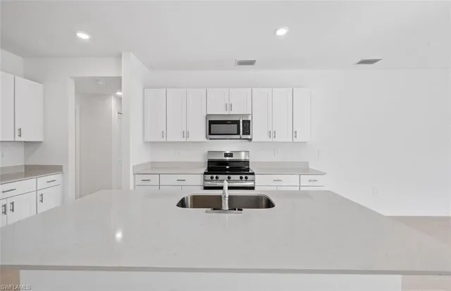 a kitchen with kitchen island a stove a sink and a refrigerator
