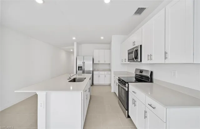 a kitchen with kitchen island white cabinets and refrigerator