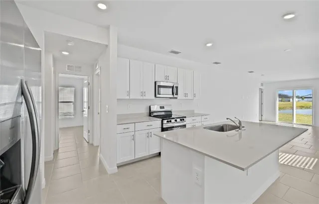 a kitchen that has a lot of white cabinets and stainless steel appliances