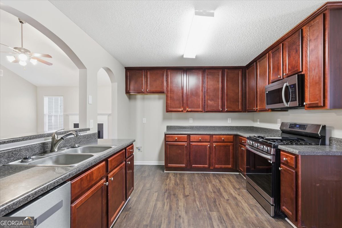 946 Damson Trail Hampton, GA 30228 - Photo 14 of 37 a kitchen with stainless steel appliances granite countertop wooden cabinets a stove top oven a sink and dishwasher