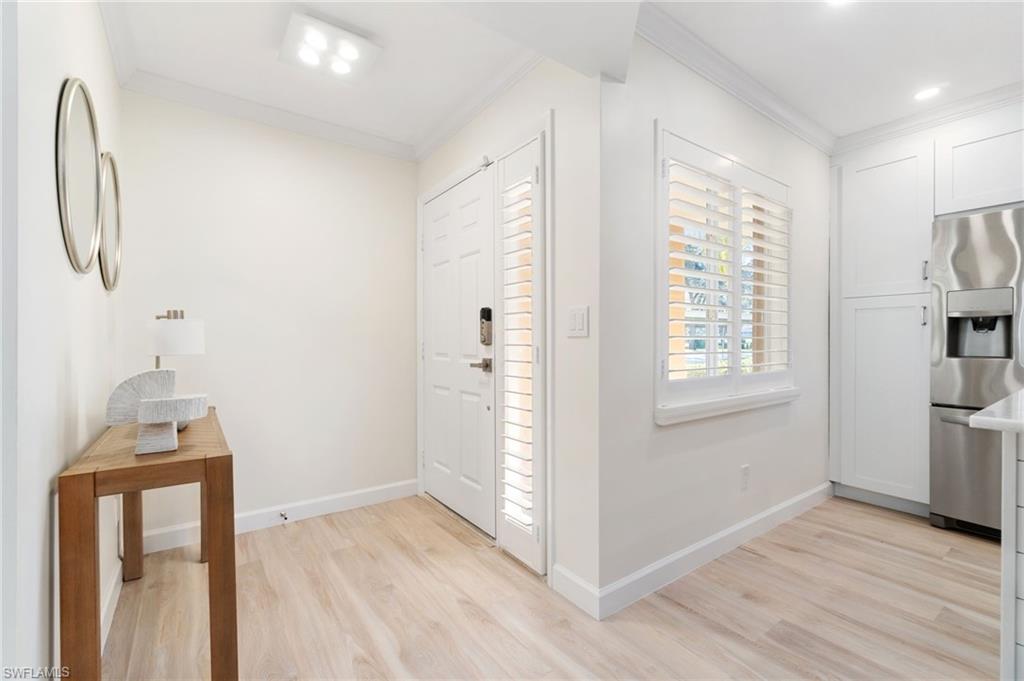 5975 Bloomfield Circle, Unit C108 Naples, FL 34112 - Photo 5 of 50 Entryway with light wood-style LVP floors and ornamental molding with new directional light fixture.