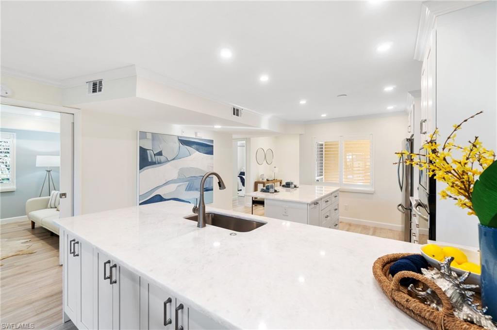 5975 Bloomfield Circle, Unit C108 Naples, FL 34112 - Photo 6 of 50 Large kitchen workspace with white marble counters, showing the entryway, front guest room, and the central den/3rd bedroom