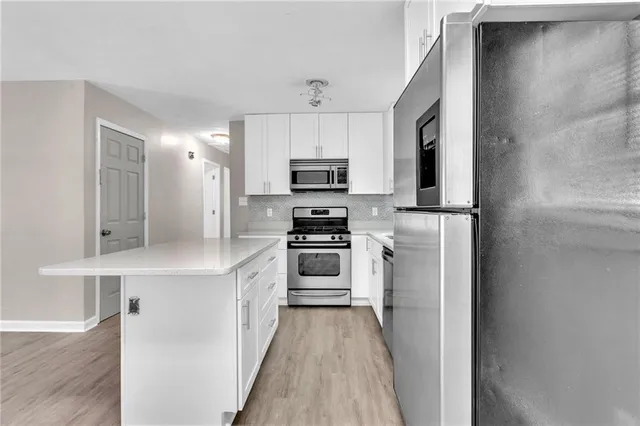 a kitchen with granite countertop a refrigerator and a stove top oven