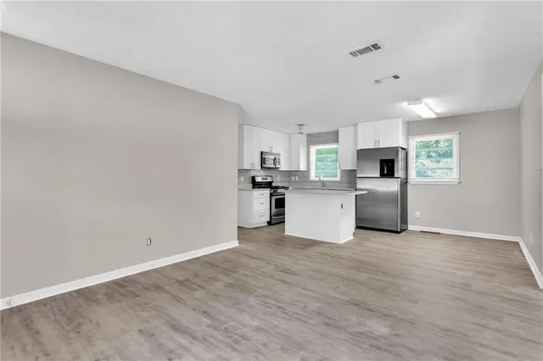 a view of a kitchen with a sink stove cabinets and empty room