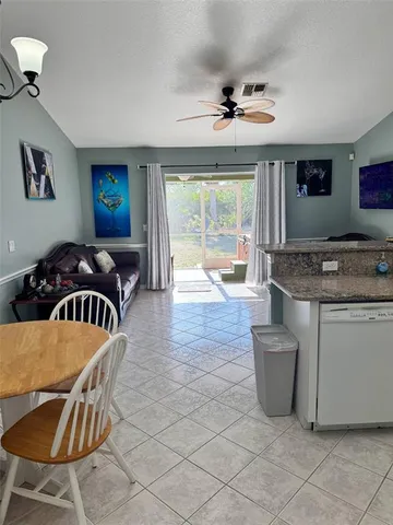 a kitchen with stainless steel appliances granite countertop a stove a sink a dining table and chairs with the front door