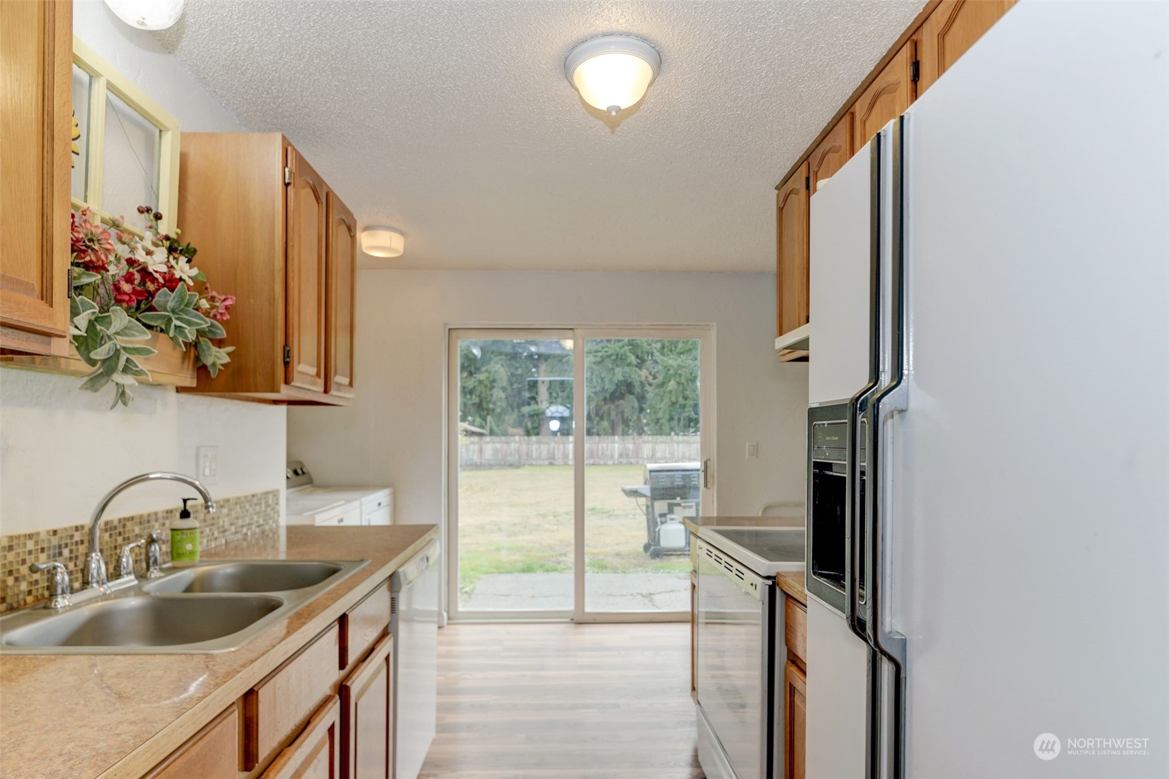 6721 183rd Avenue Southwest Rochester, WA 98579 - Photo 7 of 18 a kitchen with a sink and a refrigerator